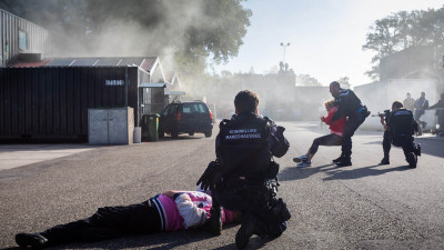 Politiemannen bieden dekking met wapens terwijl slachtoffers worden weggesleept