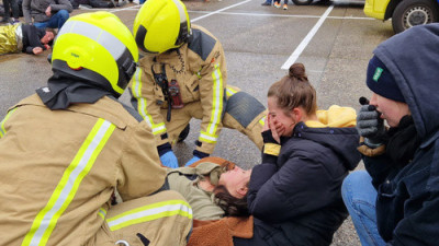 Twee aangedane mensen bij een bewusteloos slachtoffer dat door brandweer geholpen wordt