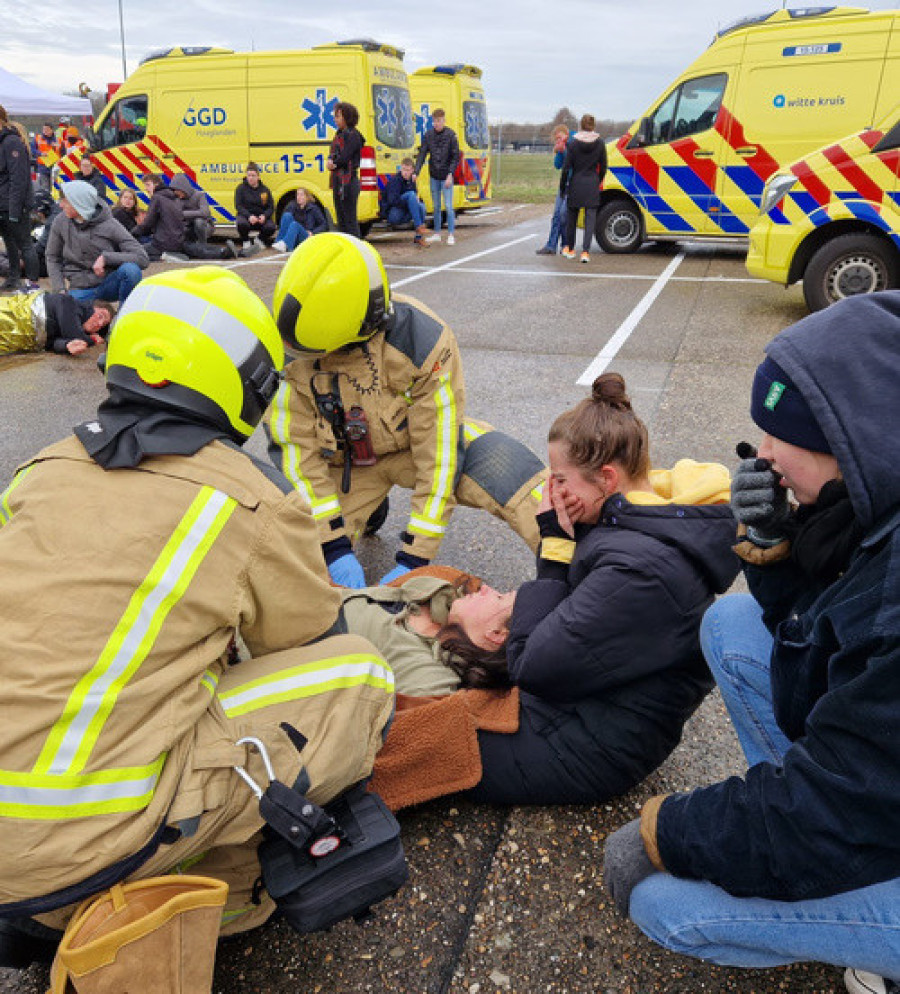 Twee aangedane mensen bij een bewusteloos slachtoffer dat door brandweer geholpen wordt