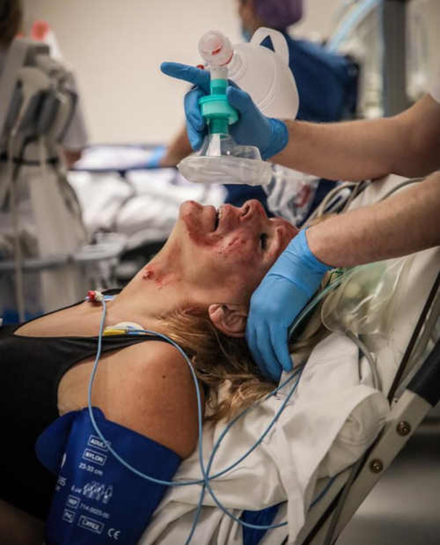 Slachtoffer met bloeddrukband om krijgt beademingsmasker in ziekenhuis