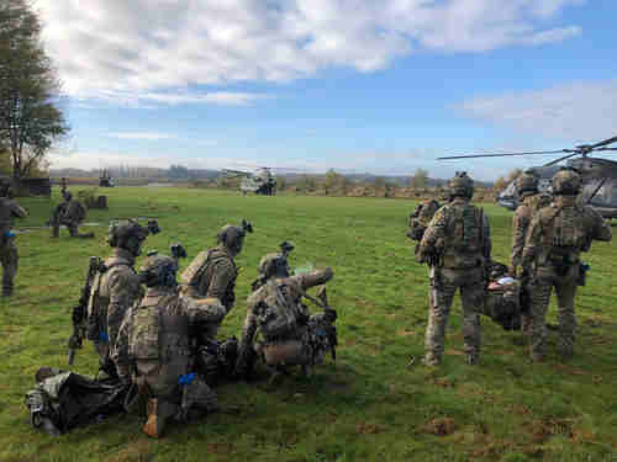 Militairen op een grasveld met helikopters